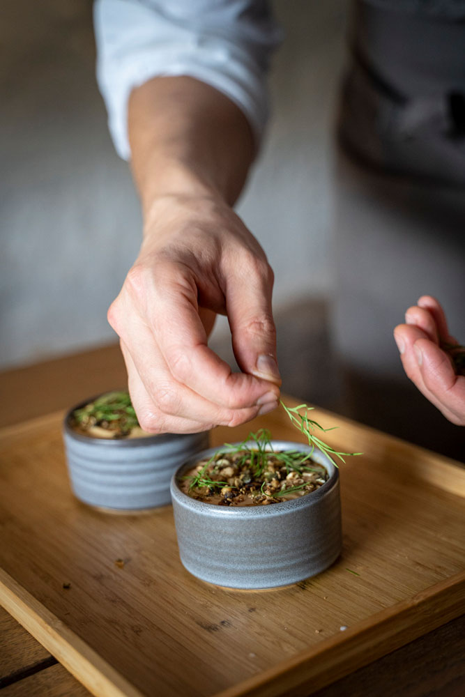 Hands of a cheff adding herbs to a dessert