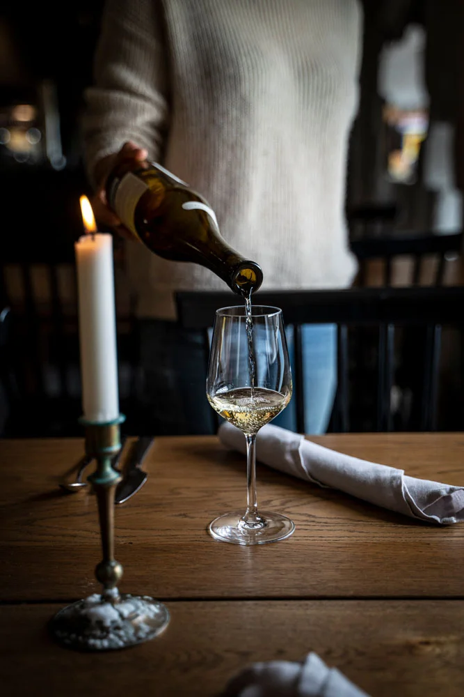 Waiter serving white wine and a candle