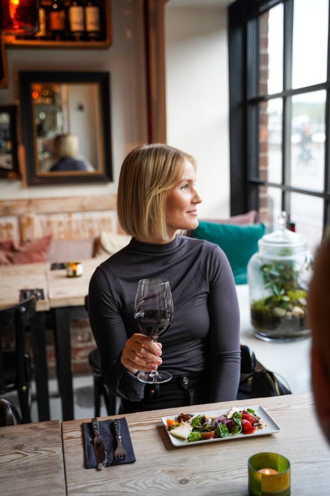 A woman holding a glass of wine in a restaurant.