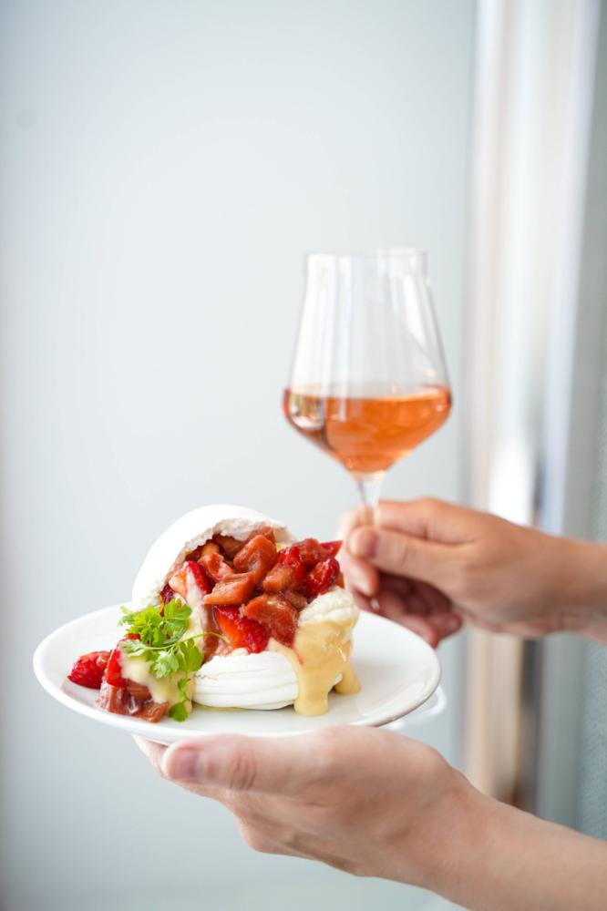 A person holding a glass of wine and a plate of food.