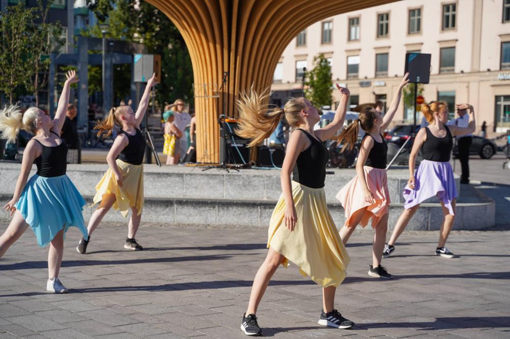 A group of dancers performing in front of a wooden structure.
